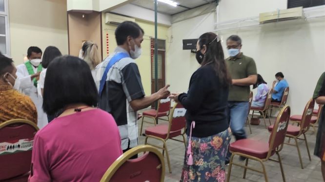 Protokol kesehatan petugas semprot handsaniteser sebelum komuni---